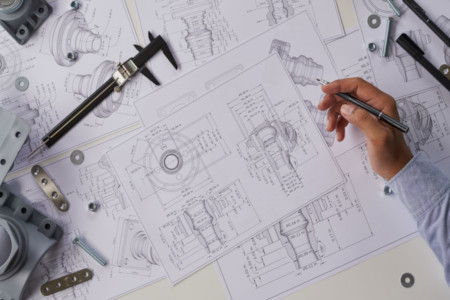 birds eye view of technical drawings laid out with vernier and various nuts and bolts on top