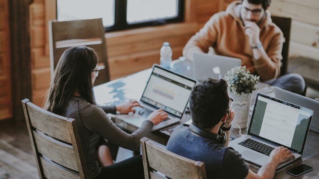Three workers working at a table with their laptops